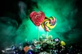 Few colorful candy heart lollipops on different colored candies against dark toned foggy background. Royalty Free Stock Photo