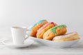 Few colorfull donuts lay on plate with cup of espresso