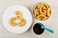 Cookies in plate, cookies in shape pretzels in bowl, spoon in bowl with chocolate sauce on table. Top view Royalty Free Stock Photo