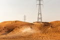 Few dune buggies driving up the sand dune in the desert, with electrical towers in the background, sunset, Fossil Rock, Sharjah, Royalty Free Stock Photo