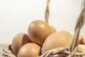 A few eggs in a wooden basket on a wooden table with white background Royalty Free Stock Photo