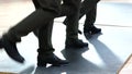 Few female tap dancers wearing pants showing various steps in studio with reflective floor.