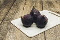 A few figs on a white desk on a wooden background