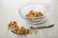 Few of granola in glass bowl, muesli in spoon on wooden table