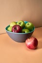 Apples lie in a bowl next to a red pomegranate Royalty Free Stock Photo