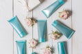 A few of the hand cream, primer, toner, face in blue, turquoise packing on a white wooden background with flowers of roses, overhe Royalty Free Stock Photo