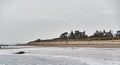 A few hardy Souls walking on a wintry, windswept beach at East haven Village Royalty Free Stock Photo