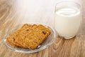 Muesli cookie in transparent saucer, glass of milk on wooden table Royalty Free Stock Photo