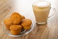 Few muffins in saucer, cappuccino in cup on wooden table