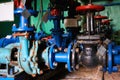 A few old black valves with red handles on a cold blue water pipe. Royalty Free Stock Photo