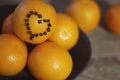 A few oranges with a heart aign made of close seeds in a gray bowl closeup on an old wooden backdround in brown with a blurred bac Royalty Free Stock Photo