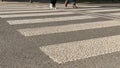 Few pedestrians cross small road by zebra crossing