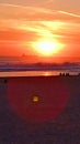 A few people watch a beautiful sunset in Lisbon on the ocean sitting on the sand Royalty Free Stock Photo