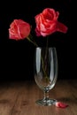 A few pink roses put in champagne glass on wooden table