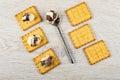 Crackers with chocolate-dairy paste, spoon with paste on wooden table. Top view