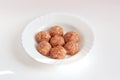 A few raw noisettes lie on a white plate. Raw meat balls with rice, spices, sauce, finely chopped cabbage are ready for cooking