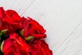 Few red roses in a corner on light wooden background with copyspace Royalty Free Stock Photo