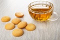 Few round biscuits, transparent cup with tea on wooden table Royalty Free Stock Photo