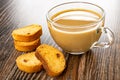 Rusks with raisin, transparent cup of coffee with milk on wooden table