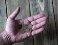 A few Russian metal rubles lie in a man`s hand over a wooden tab