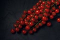 A few trusses of red wet cherry tomatoes on a dark textured background. Space for text. Top view Royalty Free Stock Photo