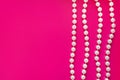 Few white pearl beads threadson a bright pink background. Glamorous background for processing Royalty Free Stock Photo