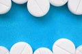 A few white tablets lie on a bright blue background surface. Background image on medical and pharmaceutical topics