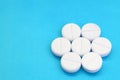 A few white tablets lie on a bright blue background surface. Background image on medical and pharmaceutical topics