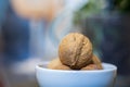 A few whole walnuts in a round-shaped brown shell lie in a small white platter on blue green blurred bokeh background Royalty Free Stock Photo