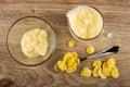 Few yogurt in transparent bowl, pitcher with yogurt, corn flakes in spoon on wooden table. Top view Royalty Free Stock Photo