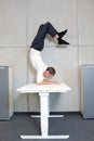 Fexible business man in scorpion asana on electric height adjustable desk Royalty Free Stock Photo