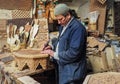 Fez, Morocco - January 07, 2020: Unknown man in his wood working or carving workshop near street market. many wooden souvenirs and