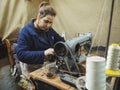 Fez, Morocco - January 07, 2020: Unknown young woman working with sewing machine, mending clothes to be sold at her market stall