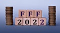 FFF 2022 - acronym on wooden cubes on a light background with coins