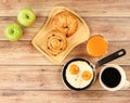 Ffried eggs , lattee coffee, orange juice ,croissant and danish pastry and two apples on wooden table Royalty Free Stock Photo