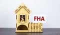 FHA, federal housing administration symbol. White paper with word `FHA, federal housing administration` near miniature house. Royalty Free Stock Photo