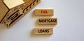 FHA mortgage loans symbol. Wooden blocks with words `FHA mortgage loans` near miniature house. Beautiful white background, copy