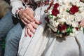 Fiance and the bride hold in hand wedding bouquet of biege and red roses.