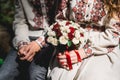 Fiance and the bride hold in hand wedding bouquet of biege and red roses.