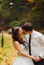 Fiance kisses a bride holding her hand in an autumn park