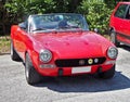 Fiat 124 Sport Spider, convertible car produced from Sixties to Eighties in a roadside parking lot,