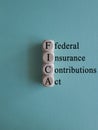 FICA symbol. Concept words FICA federal insurance contributions act on wooden cubes on beautiful blue background