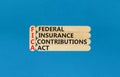 FICA symbol. Concept words FICA federal insurance contributions act on wooden stick on beautiful blue background. Business FICA