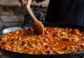 Fideua from Spain recipe, fry vegetables in a big paella pan with wood spoon Royalty Free Stock Photo