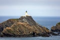 Fidra Lighthouse on top of a cliff in the United Kingdom with the sea and horizon in background