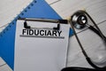 Fiduciary text write on a paperwork and stethoscope isolated on office desk