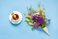 Field colorful flowers in waffle ice cream cone and cup of tea o Royalty Free Stock Photo