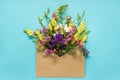 Field colorful rustic vintage flowers in craft envelope on blue