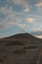 Field covered in dry grass with a hill under a cloudy sky during the sunset on the background Royalty Free Stock Photo