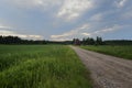 Field, dirt road and two red barns in Finland